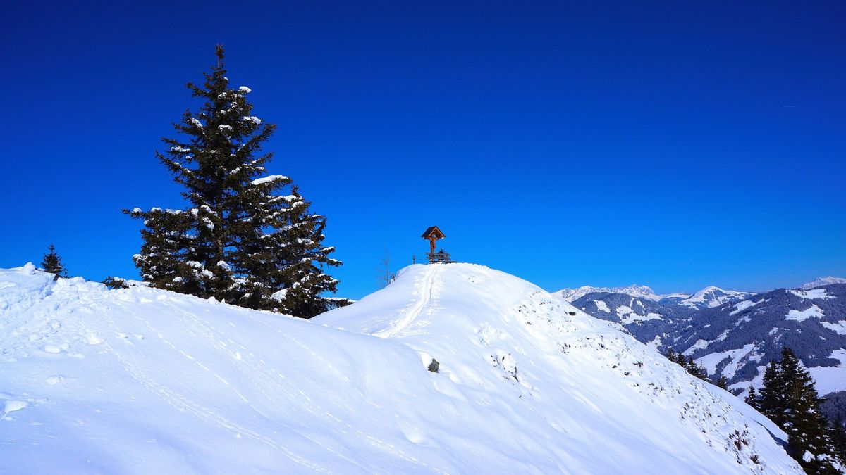 Skitourengeher auf einem verschneiten Gipfel in der Wildschönau